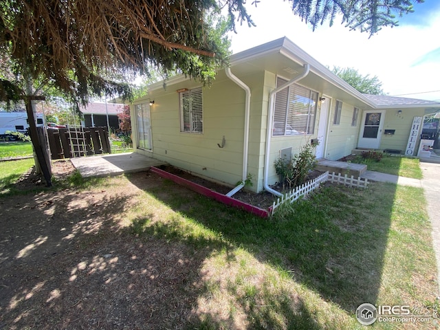 view of side of property with a patio area and a lawn