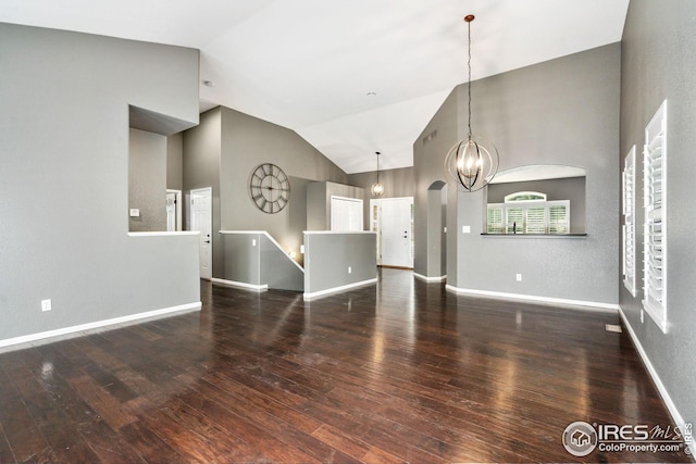 unfurnished living room with dark hardwood / wood-style flooring, high vaulted ceiling, and a notable chandelier