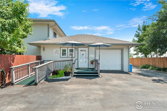 view of front of house featuring a garage, fence, and aphalt driveway