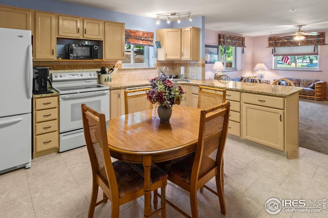 kitchen featuring light brown cabinets, plenty of natural light, tasteful backsplash, and white appliances