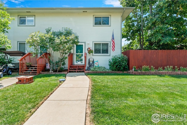 view of front of home with a front yard and fence