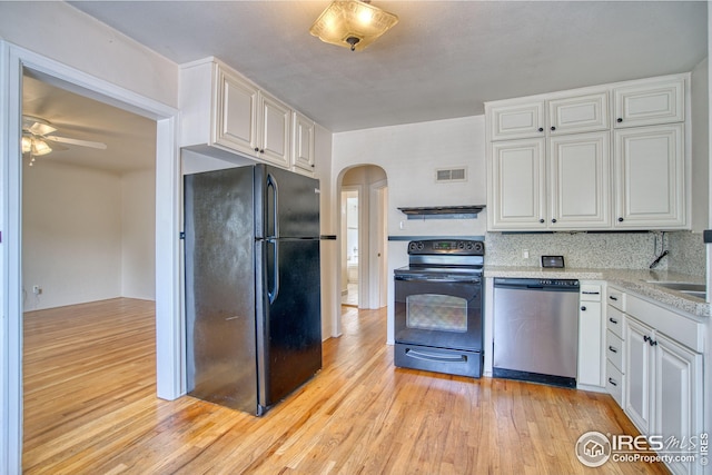 kitchen featuring light wood-type flooring, black appliances, white cabinetry, and arched walkways