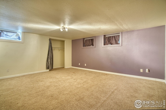 basement with a textured ceiling, baseboards, and carpet flooring