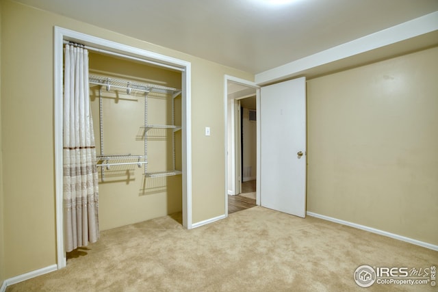 unfurnished bedroom with carpet, a closet, and baseboards