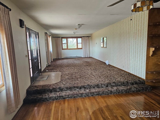 interior space with hardwood / wood-style floors, ceiling fan, and a baseboard heating unit