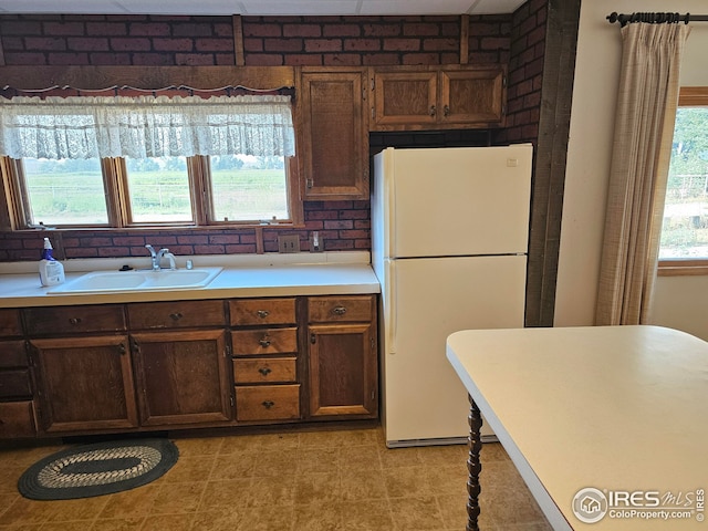 kitchen with white refrigerator, a healthy amount of sunlight, and sink