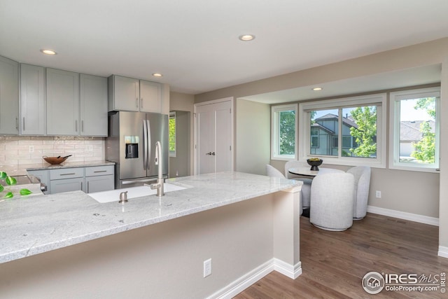 kitchen featuring light stone countertops, stainless steel fridge with ice dispenser, gray cabinets, and dark hardwood / wood-style flooring