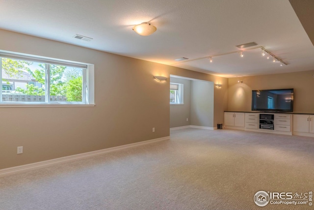 unfurnished living room with rail lighting and light carpet