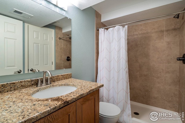 bathroom featuring walk in shower, a textured ceiling, vanity, and toilet