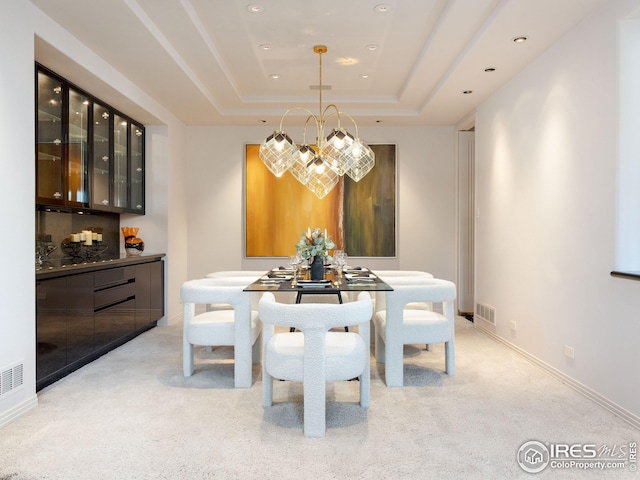 carpeted dining area featuring a raised ceiling and an inviting chandelier