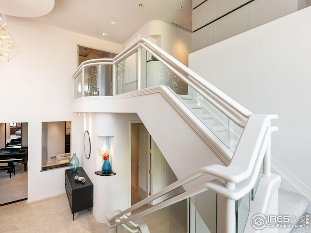 stairway featuring tile patterned flooring and a towering ceiling