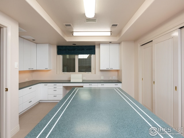 kitchen with light tile patterned floors and white cabinetry