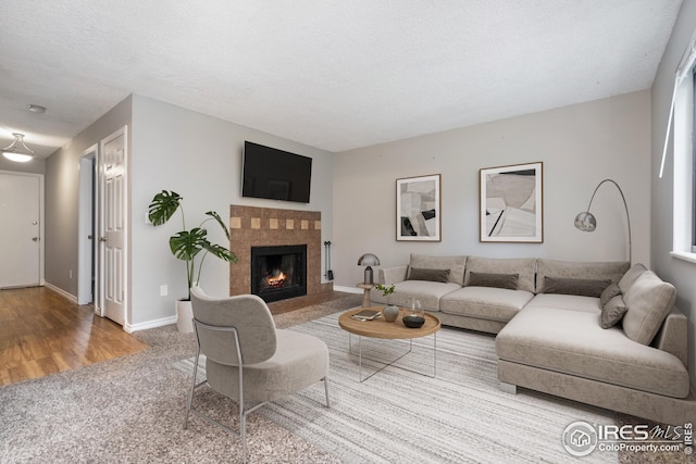 living room featuring hardwood / wood-style floors, a textured ceiling, and a tile fireplace