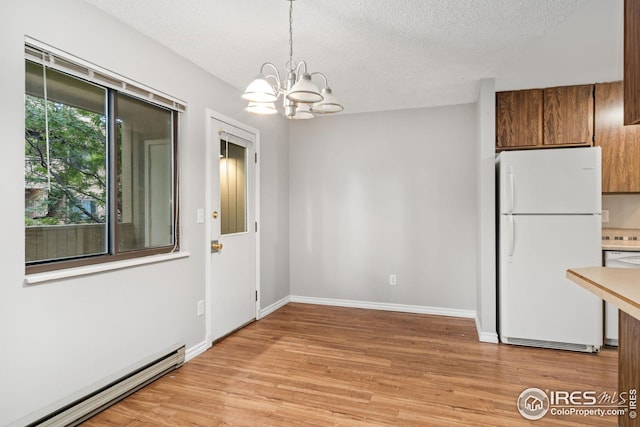 unfurnished dining area with a chandelier, a baseboard radiator, light wood-type flooring, and a textured ceiling