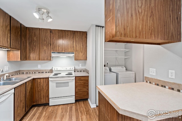 kitchen with white appliances, washing machine and dryer, light wood-type flooring, and sink