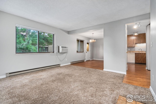 unfurnished room with baseboard heating, wood-type flooring, and a textured ceiling