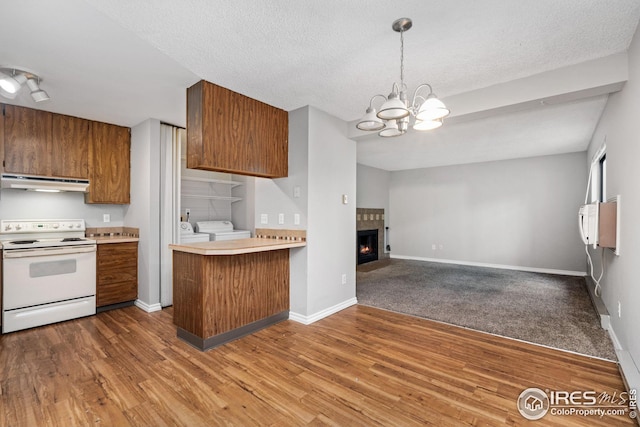 kitchen featuring dark wood-type flooring, kitchen peninsula, washer and clothes dryer, and electric range