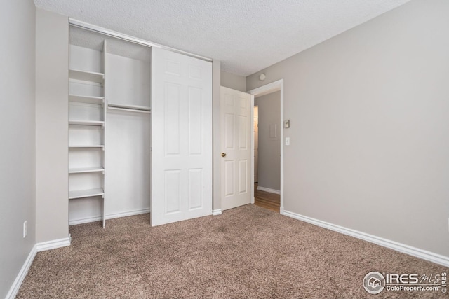 unfurnished bedroom featuring carpet floors, a textured ceiling, and a closet