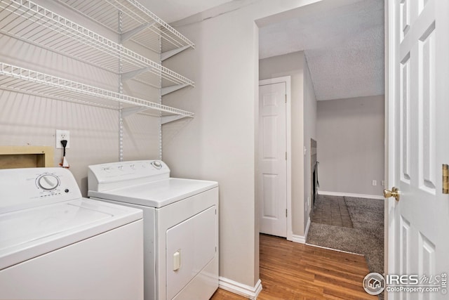 clothes washing area featuring wood-type flooring, a textured ceiling, and washing machine and clothes dryer