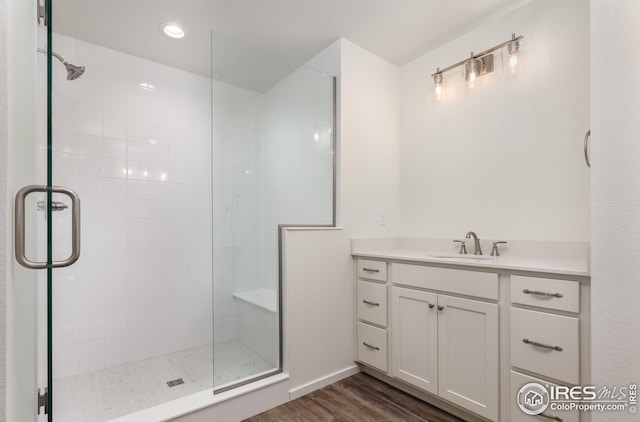 full bath with a stall shower, vanity, and wood finished floors