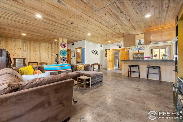 living room featuring finished concrete flooring, wooden walls, wooden ceiling, and recessed lighting