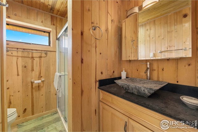 full bath with wooden walls, toilet, wood ceiling, vanity, and a shower stall