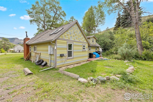 view of side of property with a mountain view and a lawn