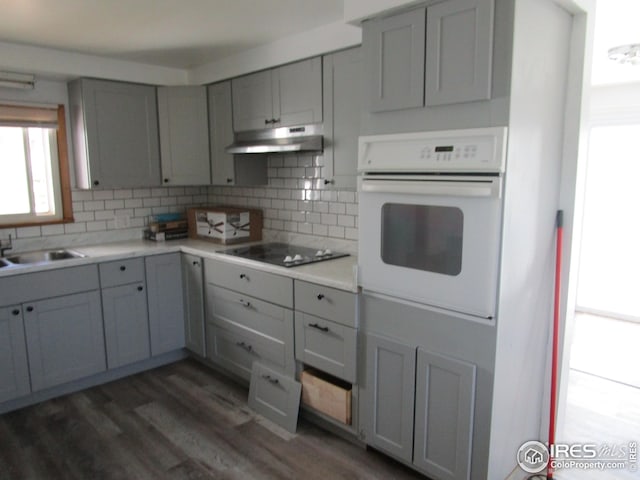 kitchen featuring gray cabinets, decorative backsplash, dark hardwood / wood-style flooring, and oven