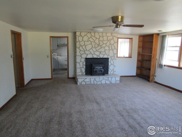 unfurnished living room featuring ceiling fan, a fireplace, and carpet