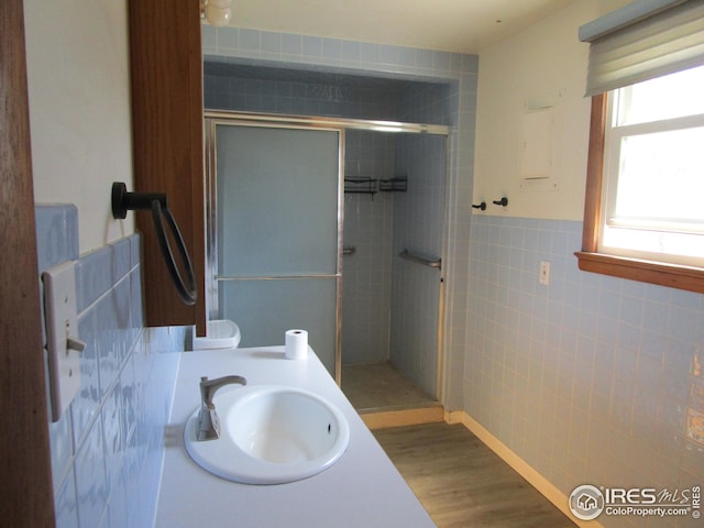 bathroom featuring tile walls, a shower with door, hardwood / wood-style flooring, and sink