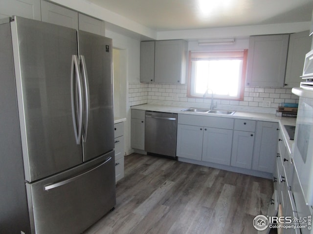 kitchen with hardwood / wood-style floors, sink, stainless steel appliances, and tasteful backsplash