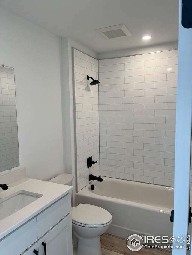 full bathroom featuring toilet, tiled shower / bath, hardwood / wood-style flooring, and vanity