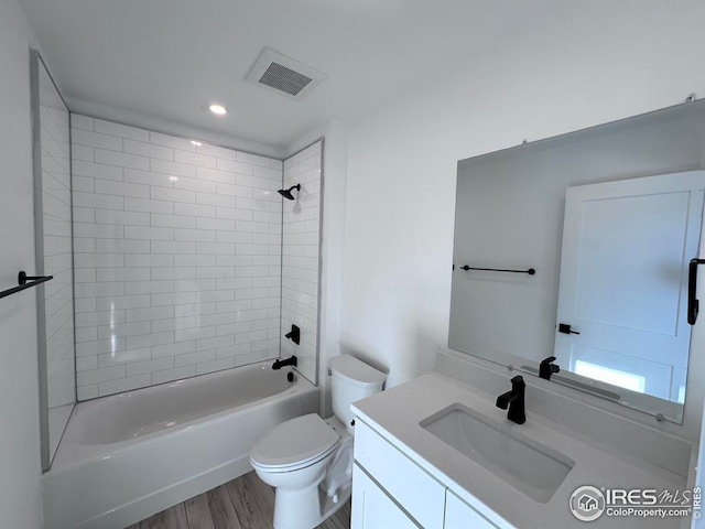 full bathroom featuring vanity, tiled shower / bath, hardwood / wood-style floors, and toilet