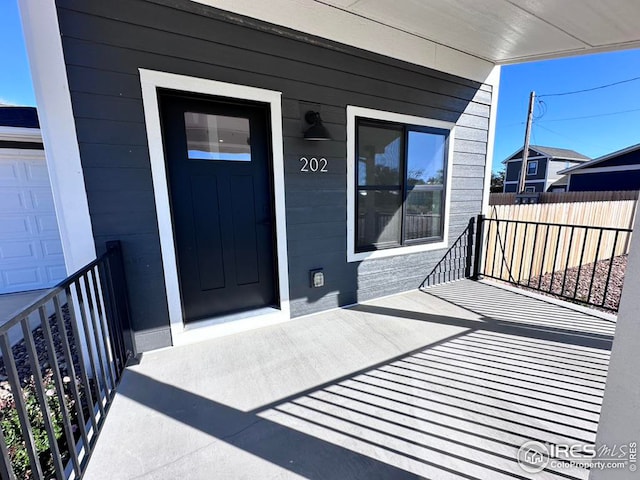 view of exterior entry featuring a porch and a garage