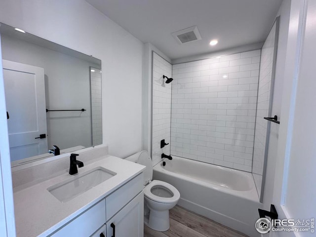 full bathroom with vanity, toilet, hardwood / wood-style flooring, and tiled shower / bath combo