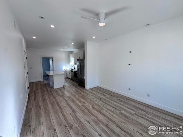 unfurnished living room featuring sink, light hardwood / wood-style flooring, and ceiling fan