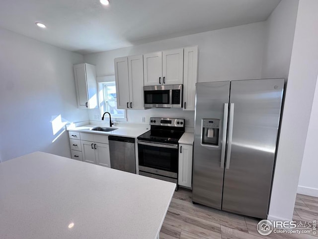 kitchen featuring white cabinetry, appliances with stainless steel finishes, sink, and light wood-type flooring