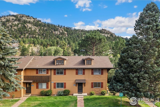 view of front of house featuring a balcony, a mountain view, and a front yard