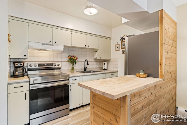 kitchen with decorative backsplash, light hardwood / wood-style flooring, a baseboard radiator, sink, and stainless steel appliances