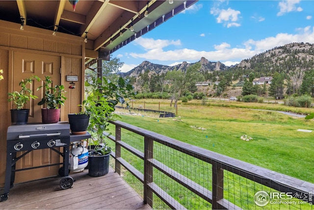 wooden deck featuring a mountain view and a yard