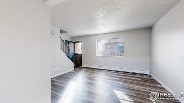 spare room featuring a textured ceiling, dark hardwood / wood-style floors, and a baseboard heating unit