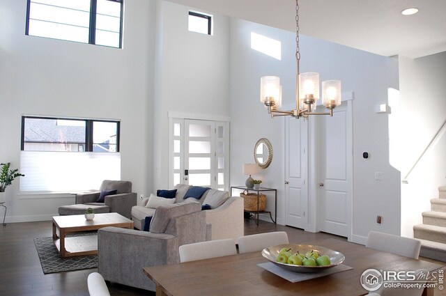 dining space featuring a towering ceiling, plenty of natural light, and dark wood-type flooring