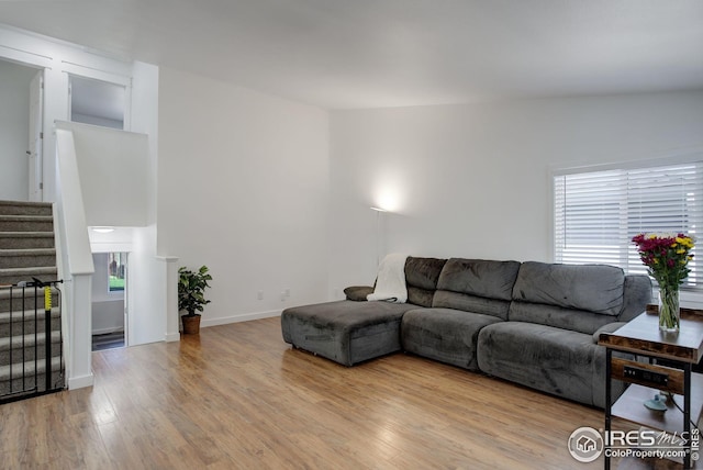 living room featuring light hardwood / wood-style flooring, vaulted ceiling, and a healthy amount of sunlight