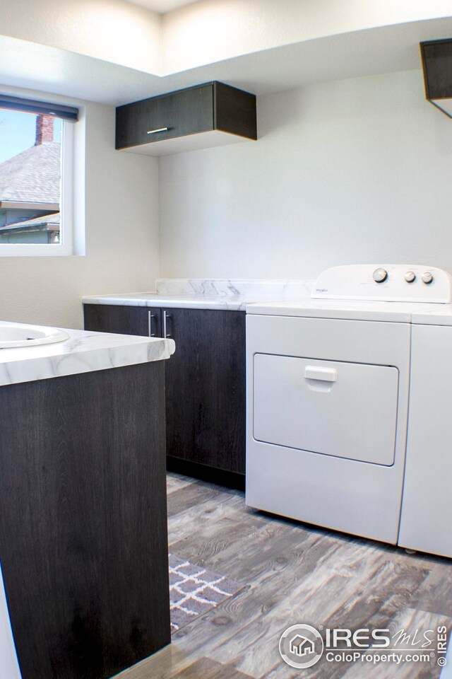 clothes washing area with light wood-type flooring, washer and clothes dryer, and sink