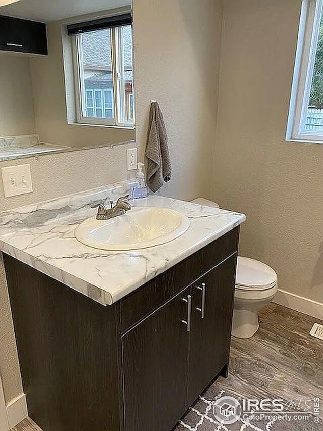 bathroom with toilet, hardwood / wood-style flooring, an AC wall unit, and vanity