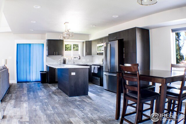 kitchen featuring dark hardwood / wood-style floors, decorative light fixtures, a center island, stainless steel appliances, and sink