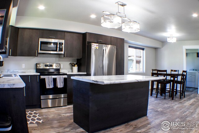 kitchen featuring a kitchen island, wood-type flooring, separate washer and dryer, and appliances with stainless steel finishes