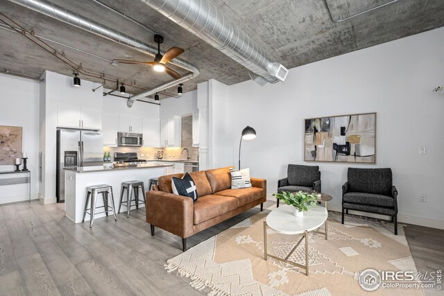 living room featuring light wood-type flooring, sink, and ceiling fan