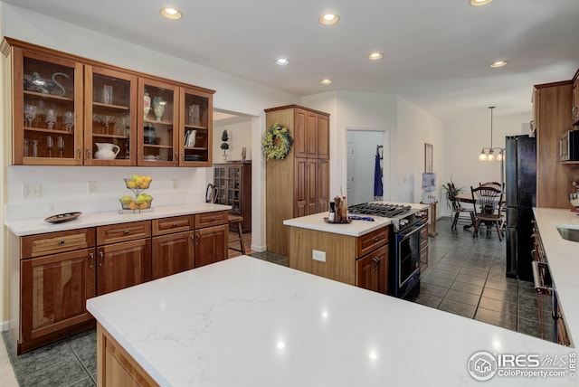 kitchen featuring dark tile patterned flooring, black refrigerator, decorative light fixtures, a center island, and gas range