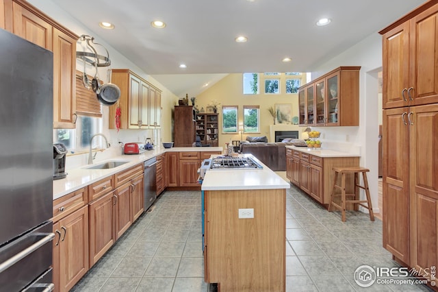 kitchen with a kitchen island, vaulted ceiling, appliances with stainless steel finishes, a breakfast bar, and sink